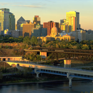 A golden hour image of the Alberta legislature, Edmonton downtown and the high level bridge, there's a small amount of the north saskatchewan river running across the bottom of the image.